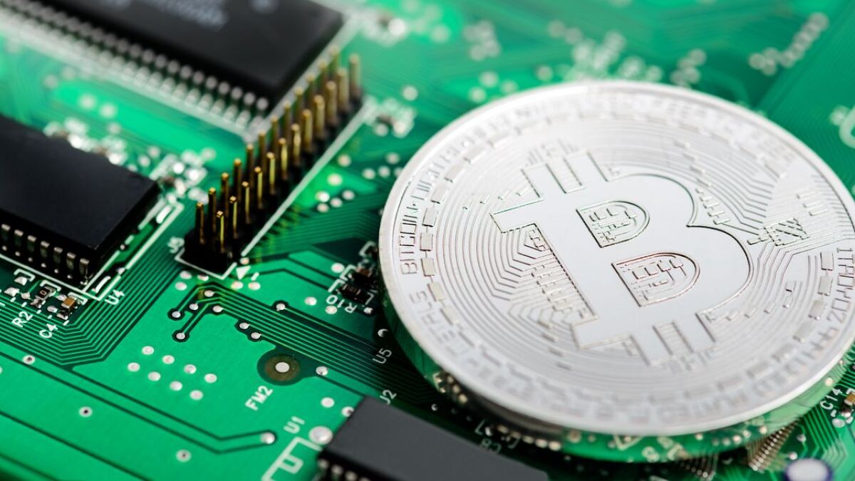 Eine silberne Bitcoin-Münze auf einer Leiterplatte.