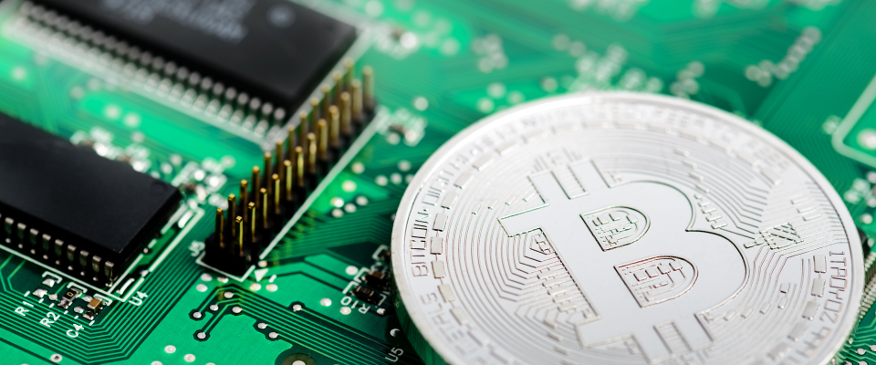 Eine silberne Bitcoin-Münze auf einer Leiterplatte.