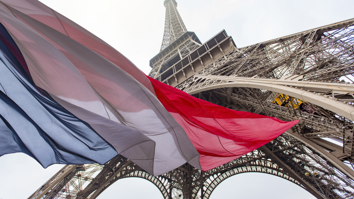 Der Eiffelturm mit der französischen Flagge im Vordergrund.