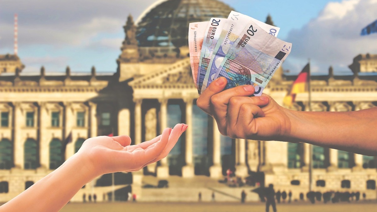 Ein Geldaustausch mit dem deutschen Reichstag im Hintergrund (Symbolbild).