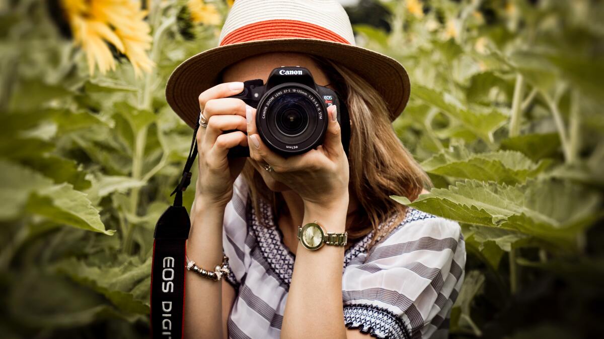 Eine Frau mit einer Kamera der Firma Canon.