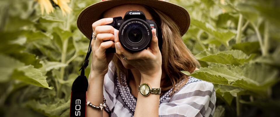 Eine Frau mit einer Kamera der Firma Canon.