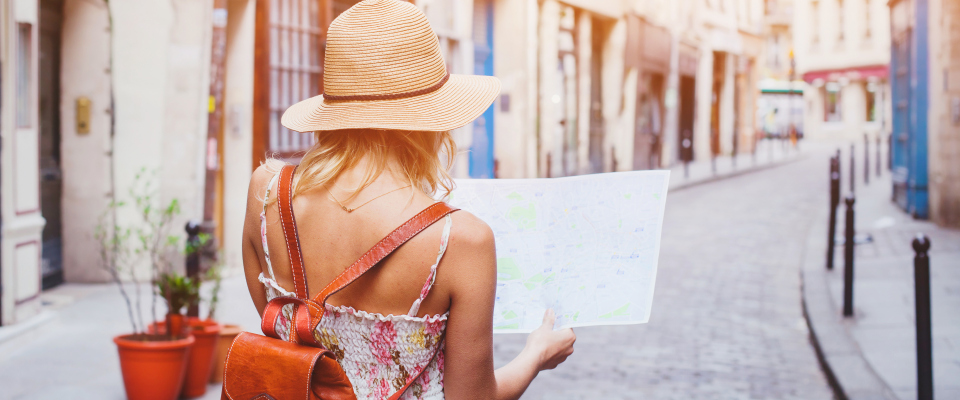 Eine Frau orientiert sich auf einer Reise auf einem Stadtplan. (Symbolbild)