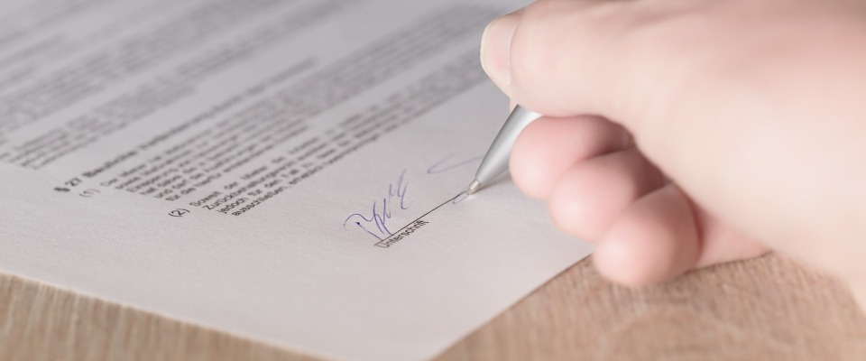 Eine Frau unterschreibt einen Vertrag (Symbolbild).