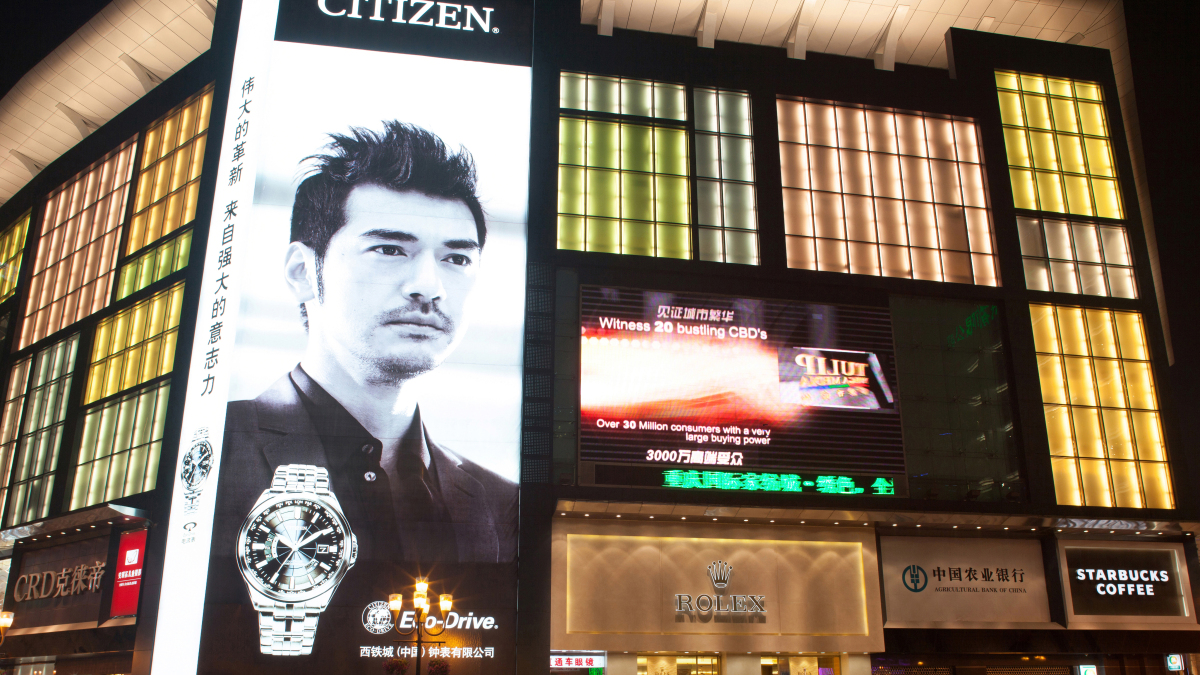 Eine beleuchtete Werbefläche für Citizen bei Nacht.